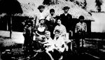 Family of tourists posed with Seminole Indians and a stuffed alligator at Musa Isle Seminole Village, 1933