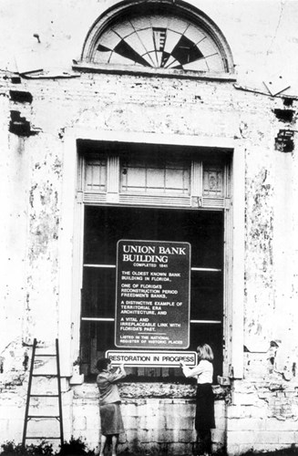 Cora Morse and Jan Dulap install a “Restoration in Progress” sign on the front of the Union Bank building during the early 1980s. Courtesy of the State Archives of Florida